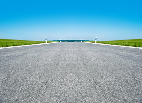 Leere, geteerte Stra&szlig;e mit Himmel und Horizont