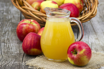 Apple juice and apples on wooden background