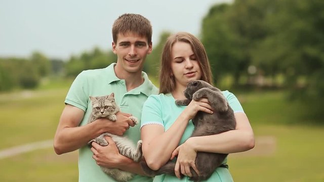 Guy and girl holding hands on the Scottish Fold cat and gray British cat.