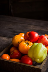Red and yellow tomatos in wooden box.