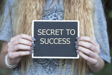 woman holding chalkboard and clock with SECRET TO SUCCESS message