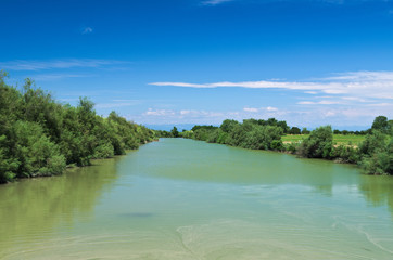 Summer view of river Lemene in the Venetian Plain with the Alps mountains in the background
