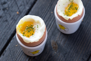 Soft boiled eggs on black wooden table. Closeup detail.