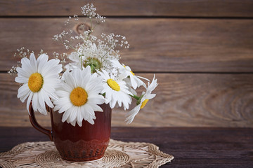 White wild daisy flowers in a vase on the old table
