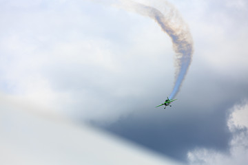 Little green plane performs aerobatics in the sky.