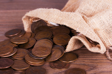 Bag of coins spilt over a wooden surface