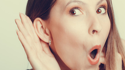 Shocked gossip girl eavesdropping with hand to ear.