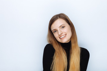 Obraz premium Portrait of happy smiling young beautiful woman in black sweater posing against white studio background