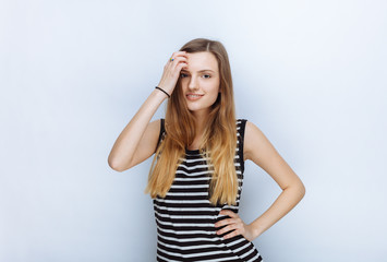 Portrait of happy young beautiful woman in striped shirt touching her hair posing for model tests against white studio background