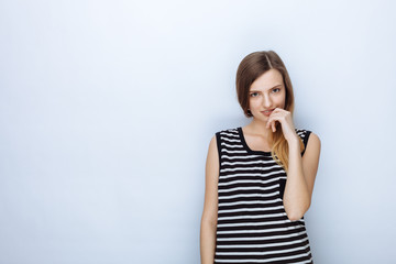 Portrait of happy young beautiful woman in striped shirt posing for model tests against white studio background