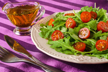 Salad of arugula and tomatoes with oil and herbs.