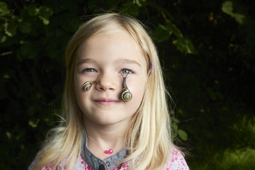 Portrait of cute blond child girl with snail on her face