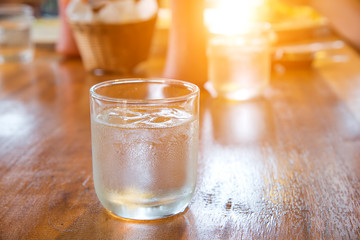 Glass water with ice on wooden table.