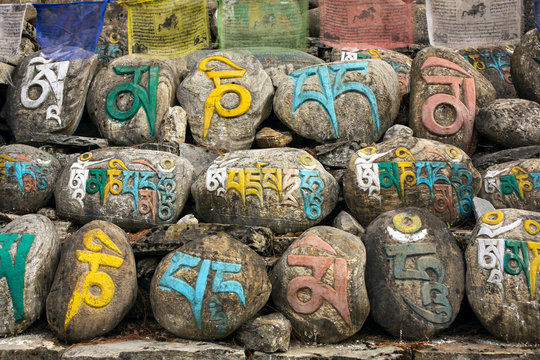 Mani stones in Nepalese village, ancient buddhist carved stones with sacred religious mantras written in Tibetan language