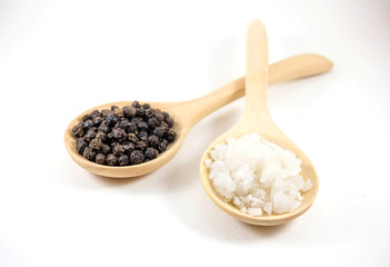 salt and pepper in a wooden spoon. Isolated on white background.