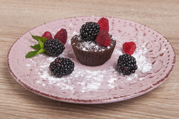 chocolate cake on a plate with raspberries and blackberries