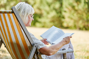 Alte Frau im Ruhestand liest ein Buch - obrazy, fototapety, plakaty
