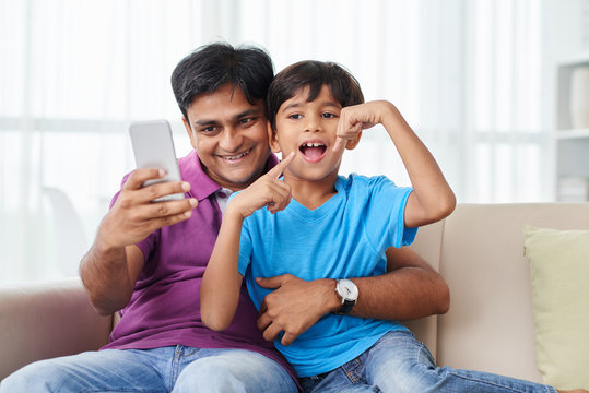 Indian father and son taking funny photos on the pone