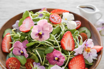Sunflower sprouts, strawberries and edible flowers salad on wooden bowl, summer light lunch, plant based diet, healthy low carb eating