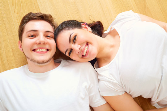 Top view of a young couple with a big smile lying on the floor l