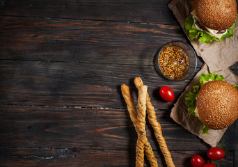 Fresh homemade burgers and breadsticks on wooden background