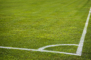 Obraz premium Football soccer field corner with white marks, green grass texture.