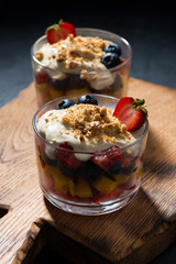 fresh fruit with custard in glasses on wooden board, vertical