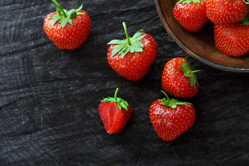 Red fresh strawberries on black rustic wood background