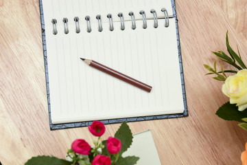 Naklejka premium Pencil and open notebook on wood background in selective focus.
