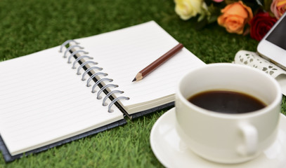 Writing on copy space note book on green grass Background.With s