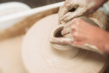 Pottery classes, student making clay pot on wheel. Close-up of dirty hands, sculpting clay crockery