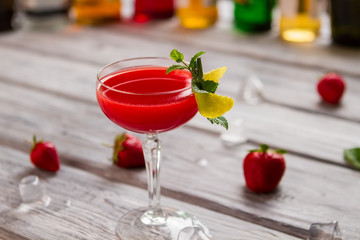 Glass with bright red beverage. Melting ice and berries. Party drink with sweet syrup. You should try clover club.