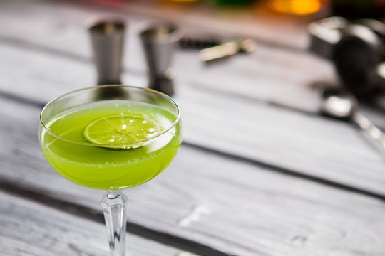 Green drink in glass. Slice of lime in beverage. Alcoholic cocktail with rum. Proven recipe of kiwi daiquiri.
