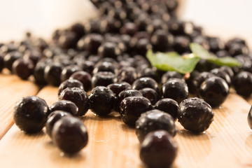 Bowl full of aronia spilled on wooden table