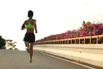 young woman runner running on city bridge road