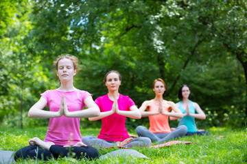 Fitness group doing yoga in park.