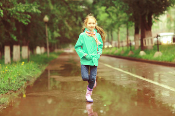 girl jumping in puddles spring rain