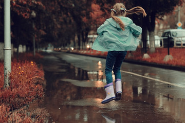 girl jumping in the puddles in the autumn rain