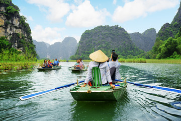 Tourists in boats. Rowers using feet to propel oars, Vietnam