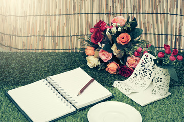 Pencil and open notebook on green grass background in selective