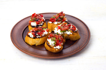 bruschetta with cheese and tomatoes on dark plate