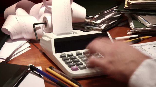Close up of a man's hand, hard at work using a calculator.