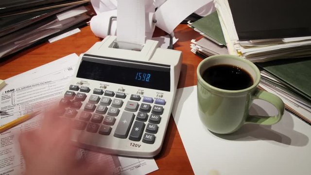 Close up of a man's hand, hard at work using a calculator.