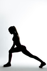 Fitness woman silhouette doing stretching exercise.
