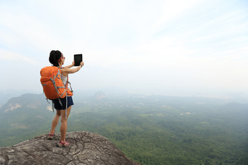 Obraz premium young woman backpacker taking photo on beautiful mountain peak