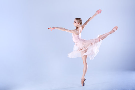 Ballet Perfection. Young and beautiful ballerina is dancing in a white studio full of light.