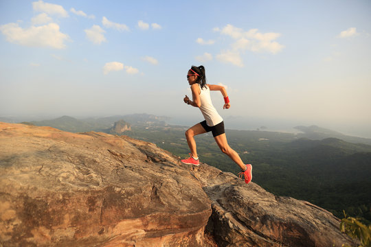 young asian woman runner running on mountain peak