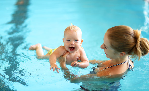 mother teaching baby swimming pool
