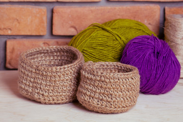 Set of knitted baskets on brick background