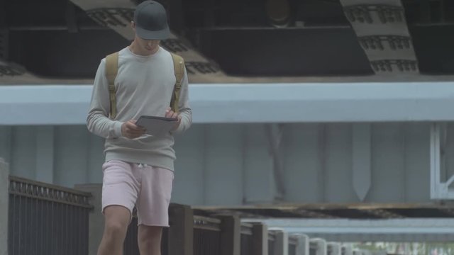 young guy in town on a skateboard with a tablet in hand in the summer